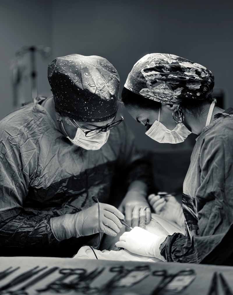 Op. Dr. Eser Ağar ameliyathanede hemşireyle birlikte ameliyat yaparken (siyah-beyaz fotoğraf)